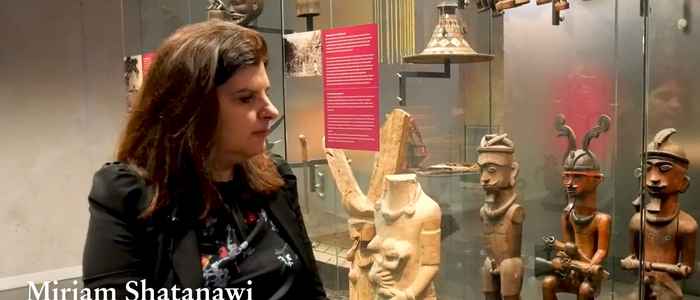 still uit de video met Mirjam Shatanawi. Ze staat voor een vitrine in museum in Leiden