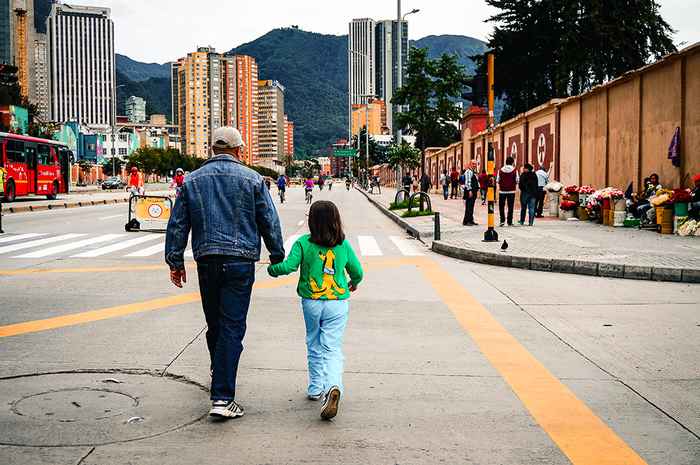 Vader en dochter lopen hand in hand door straat in Colombia