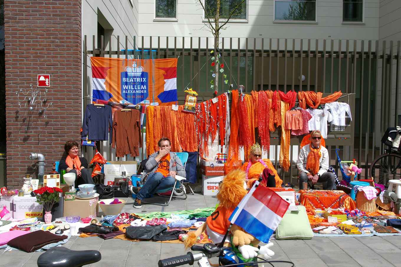 Vrijmarkt op Koningsdag in Amsterdam. In het oranje geklede Amsterdammers verkopen hun tweedehands spullen vanaf kleedjes op straat.