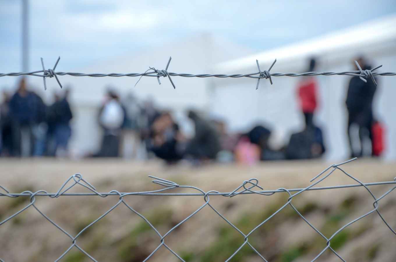 refugees in refugee camp behind fence