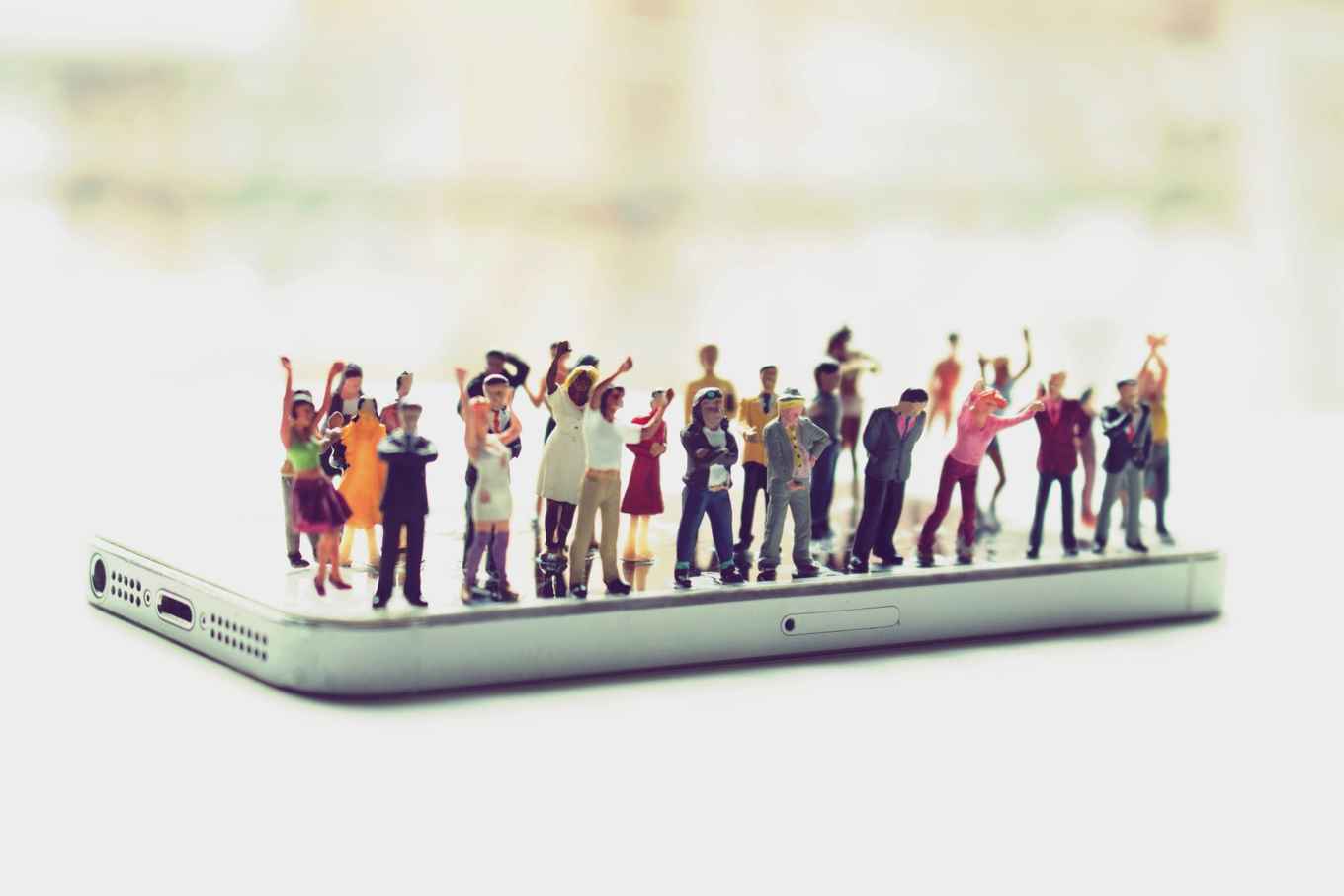 group of small figures standing on a mobile phone, shouting and with their fists in the air