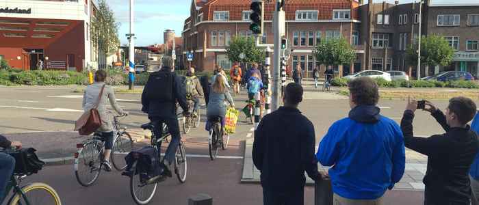 Deelnemers aan een studiebezoek uit de VS observeren een druk kruispunt tijdens een fietstocht met gids. Utrecht, Nederland