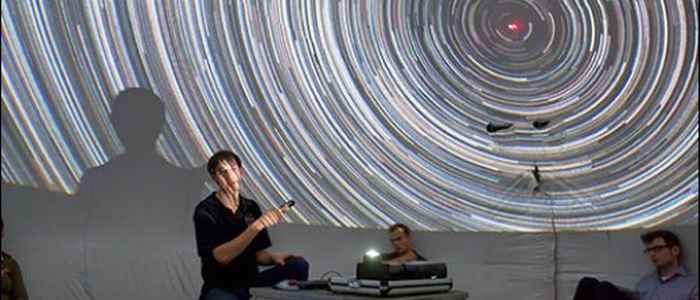 A young person pointing to a picture with star trails