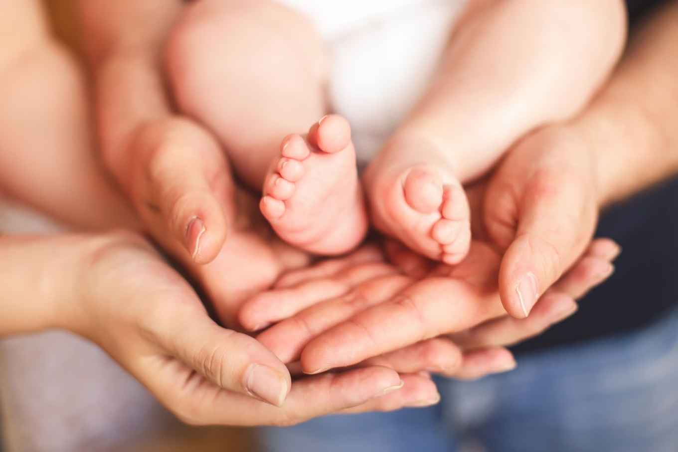 handen van ouders houden babyvoetjes vast