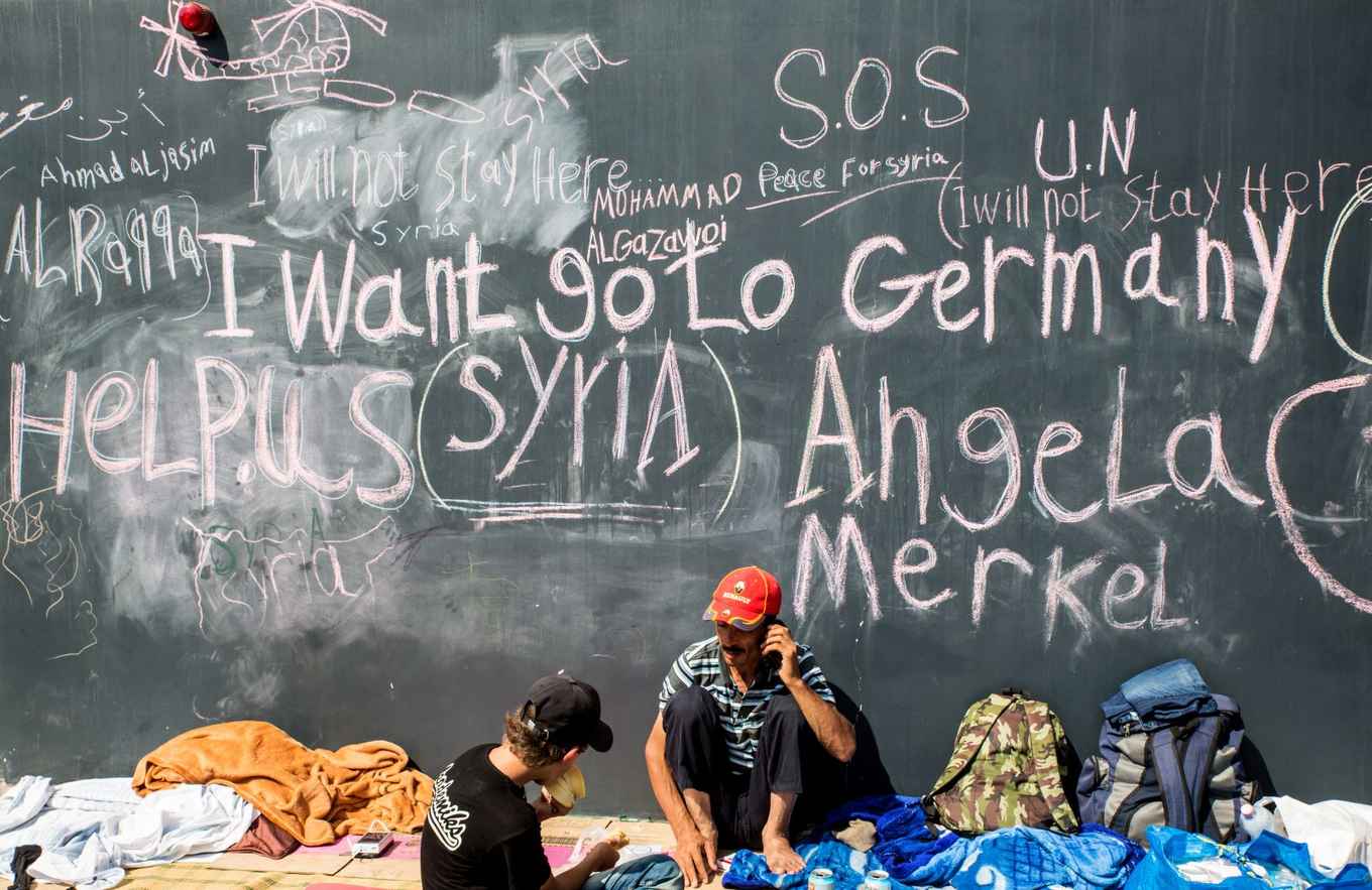 Syrische vluchtelingen vragen hulp van Duitsland, geschreven op een muur