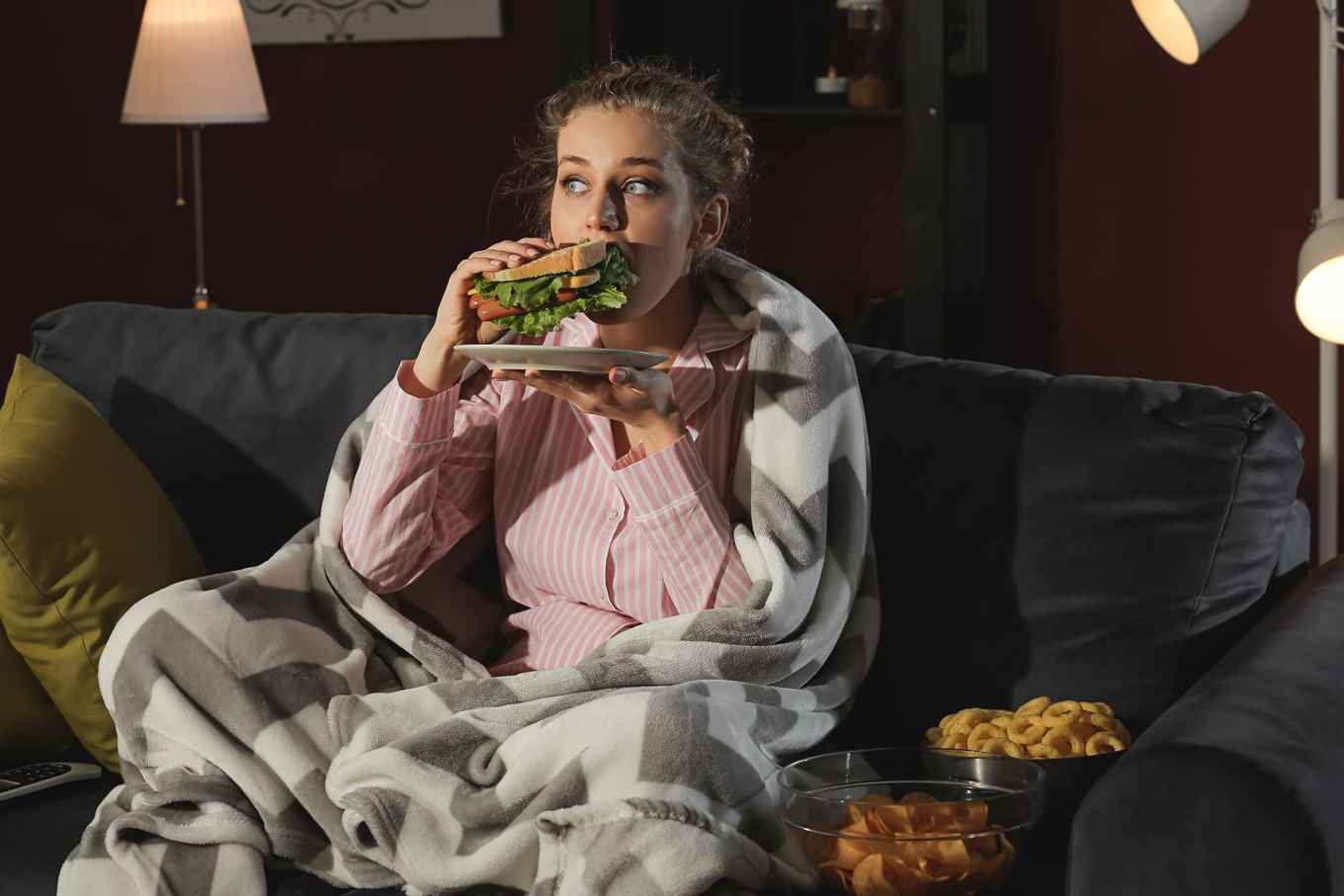 Jonge vrouw eet tijdens het televisiekijken