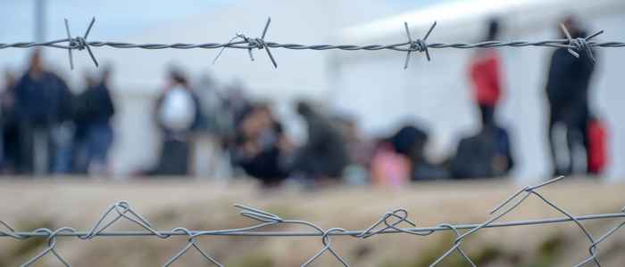 refugees in refugee camp behind fence