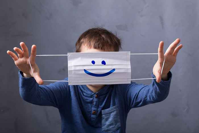 een jongetje houdt een mondkapje vast waar een glimlach op is getekend