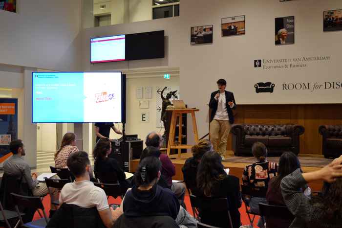Merel talbi staat op het podium en spreekt de mensen in de zaal aan.